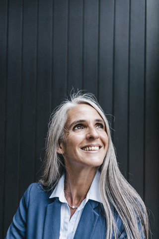 Porträt einer lächelnden Frau mit langen grauen Haaren, die nach oben schaut, lizenzfreies Stockfoto