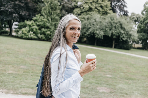 Lächelnde Frau mit Kaffee zum Mitnehmen im Park - KNSF000307