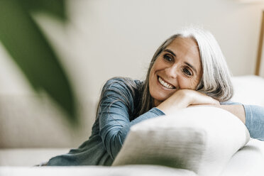 Smiling woman on the couch at home - KNSF000330