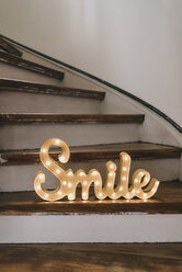 Glänzendes Wort 'Smile' auf Holzstufen - KNSF000364