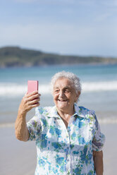 Glückliche ältere Frau nimmt Selfie am Strand - RAEF001426