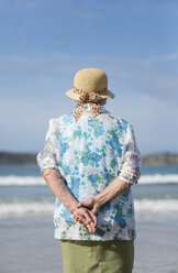 Rückenansicht einer älteren Frau mit Strohhut am Strand mit Blick in die Ferne - RAEF001430
