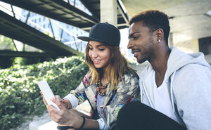Lächelndes junges Paar schaut auf Smartphone - DAPF000273