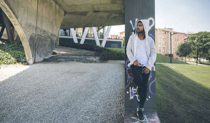 Young man wearing hooded jacket listening music with earphones - DAPF000277