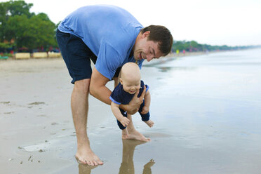 Indonesien, Bali, junger Vater und Baby am Strand - KNTF000466