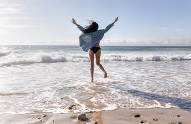 Spain, Asturias, beautiful young woman jumping on the beach - MGOF002201