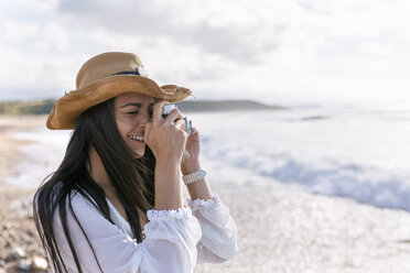 Asturien, Spanien, schöne junge Frau mit einer Kamera am Strand - MGOF002203