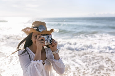 Asturien, Spanien, schöne junge Frau mit einer Kamera am Strand - MGOF002206