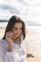 Spanien, Asturien, schöne junge Frau mit Smartphone am Strand - MGOF002210