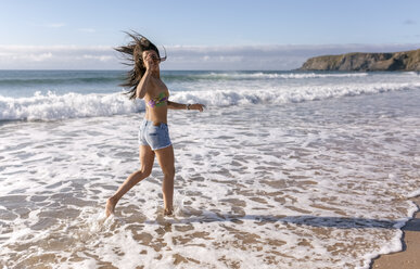 Spain, Asturias, beautiful young woman running on the beach - MGOF002215