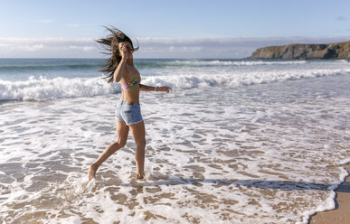 Spanien, Asturien, schöne junge Frau läuft am Strand - MGOF002215