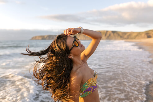 Spanien, Asturien, schöne junge Frau am Strand bei Sonnenuntergang - MGOF002231