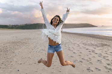 Spain, Asturias, beautiful young woman jumping on the beach - MGOF002243