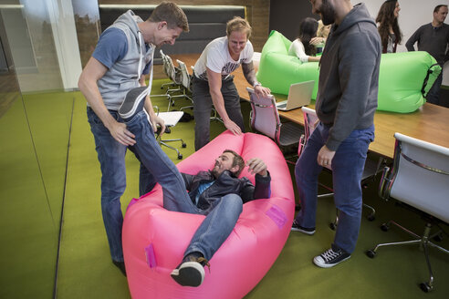 Group of business people playing around with inflatable sofas - ZEF009768