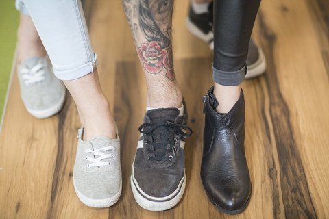 Drei Menschen zeigen ihre unterschiedlichen Schuhe, lizenzfreies Stockfoto