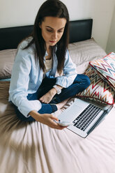Young woman using smartphone and laptop on bed - BOYF000568
