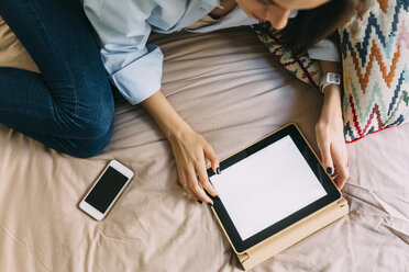 Junge Frau mit digitalem Tablet auf dem Bett, Smartphone - BOYF000578