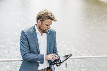 Businessman standing on bridge using tablet - KNSF000378