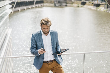 Geschäftsmann stehend auf Brücke mit Tablet und Mobiltelefon - KNSF000383