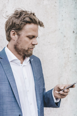 Geschäftsmann schaut auf sein Handy, lizenzfreies Stockfoto