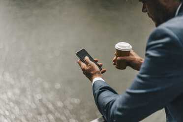 Geschäftsmann mit Handy und Kaffee zum Mitnehmen auf der Brücke - KNSF000419