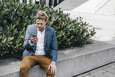 Businessman looking on cell phone - KNSF000429