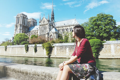 Frankreich, Paris, Frau sitzt am Ufer der Seine vor Notre-Dame de Paris - GEMF000971