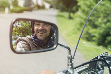 Reflexion eines lächelnden Mannes im Spiegel eines Motorrads - JUNF000581
