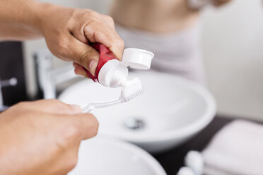 Man's hands applying toothpaste on toothbrush, close-up - JUNF000602