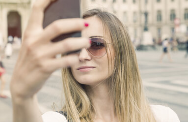 Italy, Milan, blond tourist with sunglasses taking selfie in front of Milan Cathedral - JUNF000605