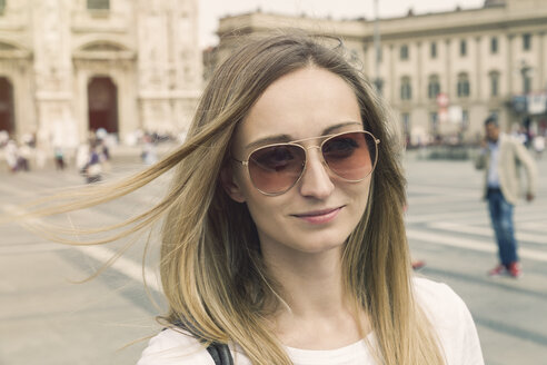 Italien, Mailand, Porträt einer lächelnden blonden Touristin mit Sonnenbrille vor dem Mailänder Dom - JUNF000606