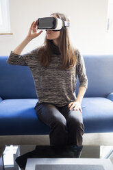 Frau sitzt auf einer Couch und trägt eine Virtual-Reality-Brille - NDF000588