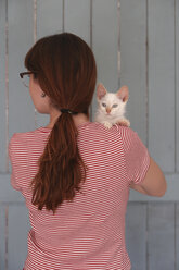 Rückenansicht einer Frau, die ein Kätzchen auf dem Arm hält - RTBF000259