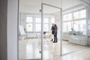 Geschäftsmann und Frau stehen in einem hellen Büro - RBF004984