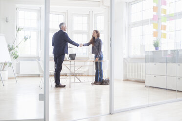 Businessman and woman shaking hands in bright office - RBF004988