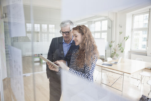 Businessman and woman using digital tablet in office - RBF004990