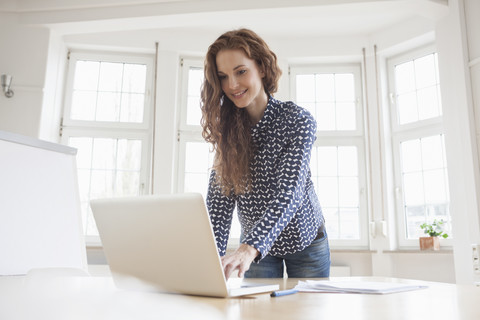 Frau benutzt Laptop im Büro, lizenzfreies Stockfoto