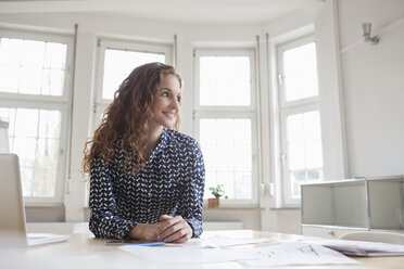Smiling woman at desk in office - RBF005001