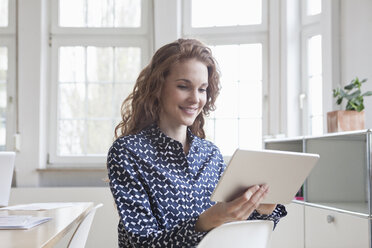 Frau schaut auf Tablet im Büro - RBF005018