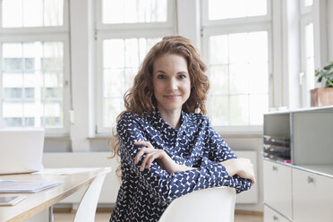 Portrait of smiling woman at desk in office - RBF005019