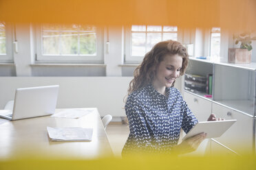 Frau schaut auf Tablet im Büro - RBF005066