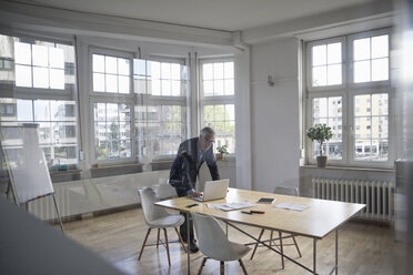 Mature businessman using laptop on boardroom table - RBF005072