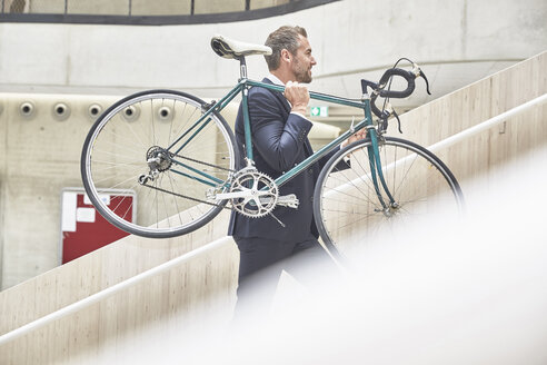 Geschäftsmann mit Fahrrad im Bürogebäude - FMKF002893