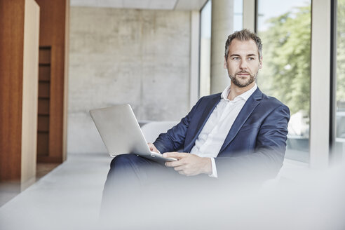 Geschäftsmann sitzend mit Laptop - FMKF002911