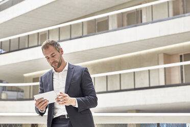 Businessman using tablet in office building - FMKF002919