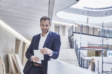 Businessman holding tablet in office building - FMKF002921