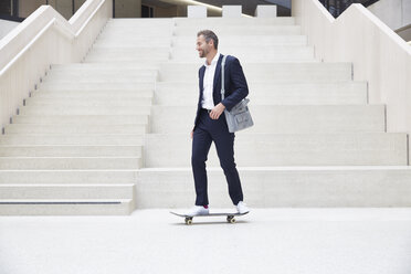 Businesssman riding skateboard at staircase - FMKF002924