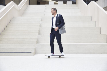 Geschäftsmann fährt Skateboard im Treppenhaus - FMKF002924
