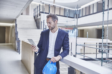 Architekt in einem Bürogebäude mit Blick auf ein Tablet - FMKF002933