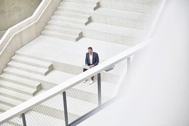 Geschäftsmann auf der Treppe sitzend mit Laptop - FMKF002940